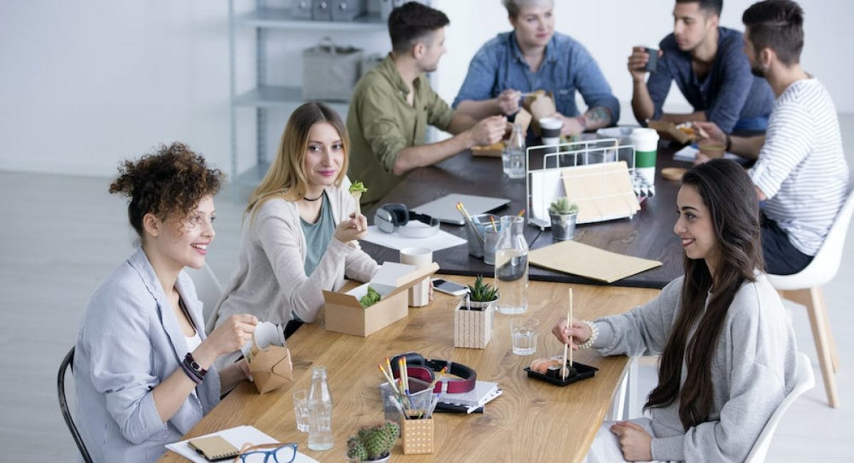 High angle of smiling women eating lunch in corporation canteen during break